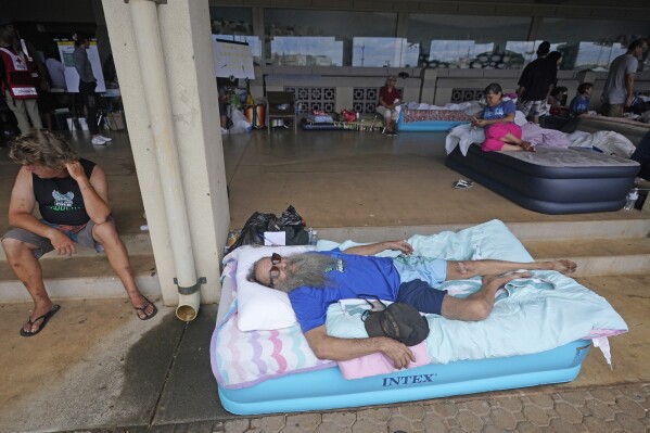 Thomas Leonard lies on an air mattress at an evacuation center at the War Memorial Gymnasium after his Lahaina apartment was destroyed by wildfire, Thursday, Aug. 10, 2023, in Wailuku, Hawaii. (AP Photo/Rick Bowmer)